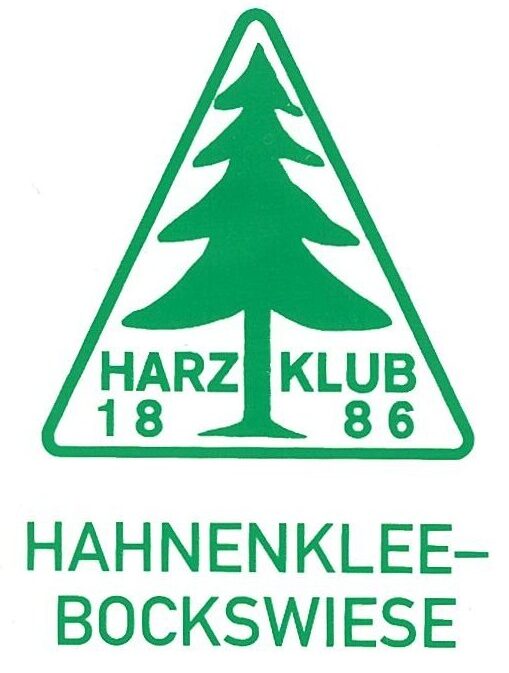 auf weißem Grund ist in grüner Schrift: 1 Dreieck mit einer Tanne darin. Text: Harzklub 1886, Gründungsjahr des Harzklubs . Darunter HAHNENKLEE-BOCKSWIESE in Großbuchstaben