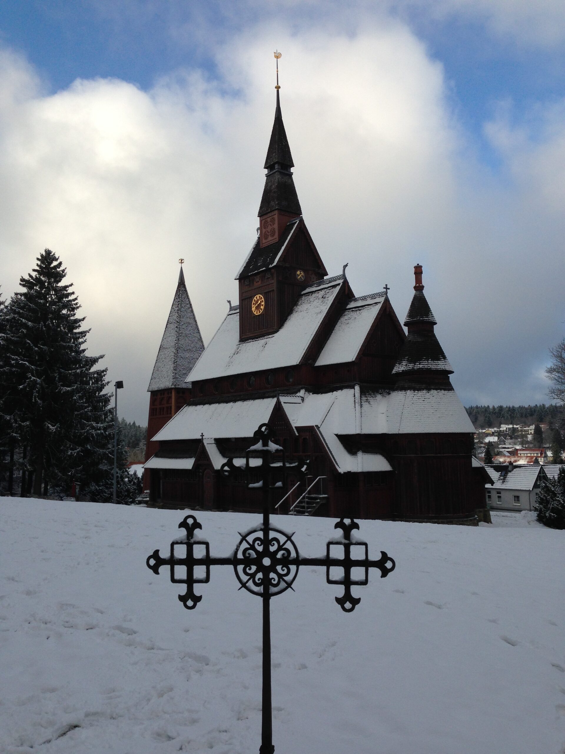 Die Hahnenkleer Nordische Stabkirche mit einem geschmiedeten Kreuz im Vordergrund