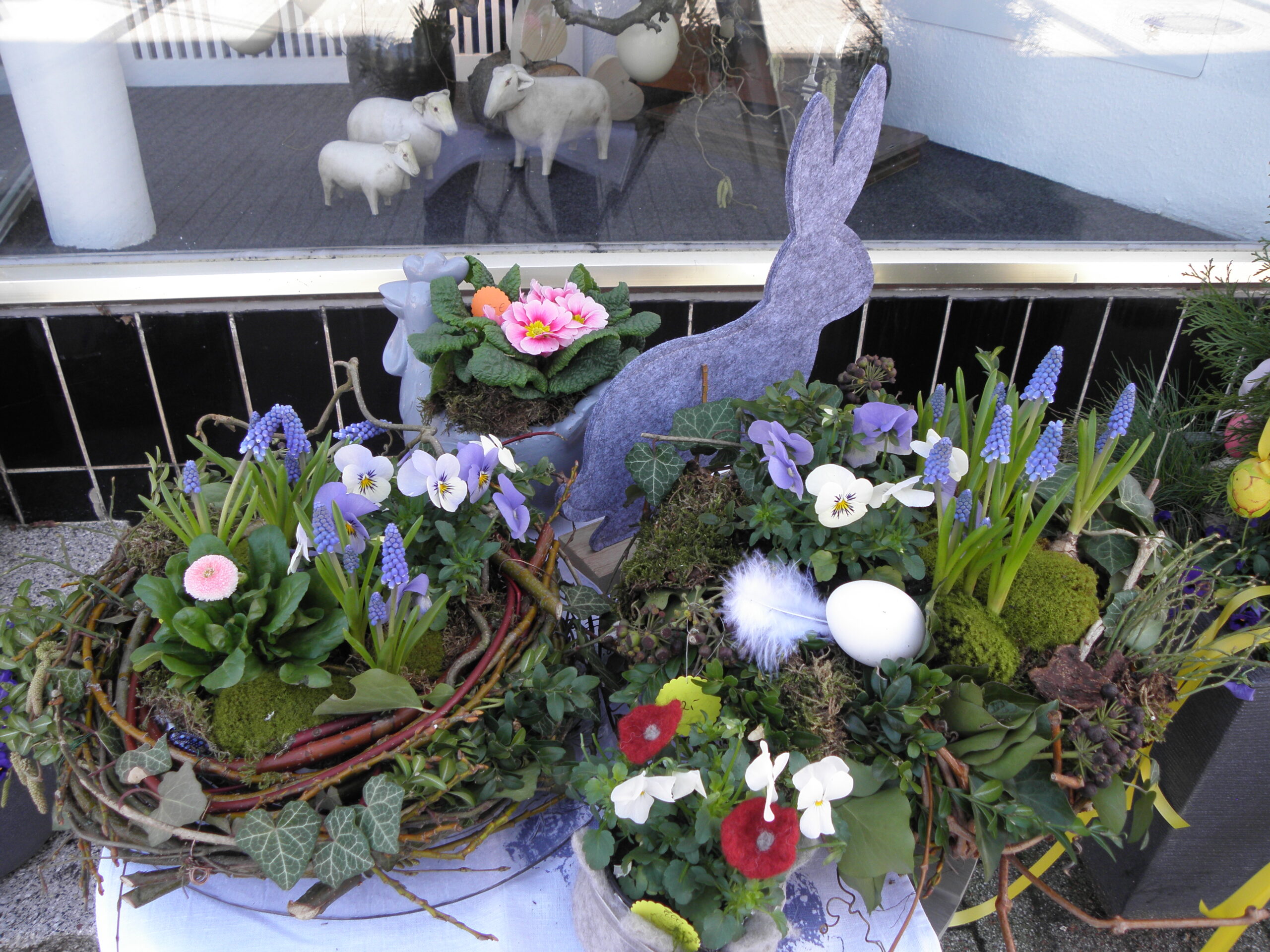 Bunte Frühlingsblumen und Ostergestecke stehen hübsch dekoriewrt zum Verkauf bereit