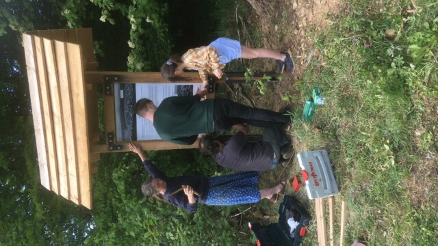 Helfer beim Aufstellen der neuen Holz-Infotafel mit Dach am Keilerstieg